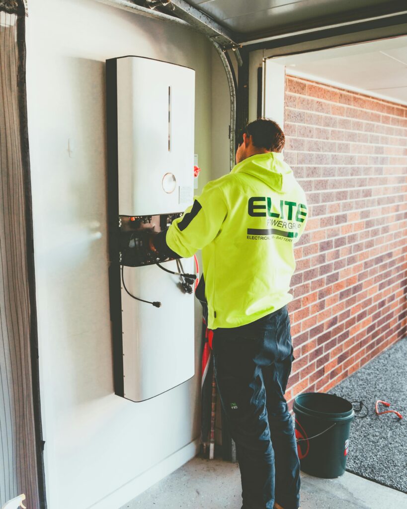 Electrician working on a solar inverter installation inside a garage in New South Wales, Australia.